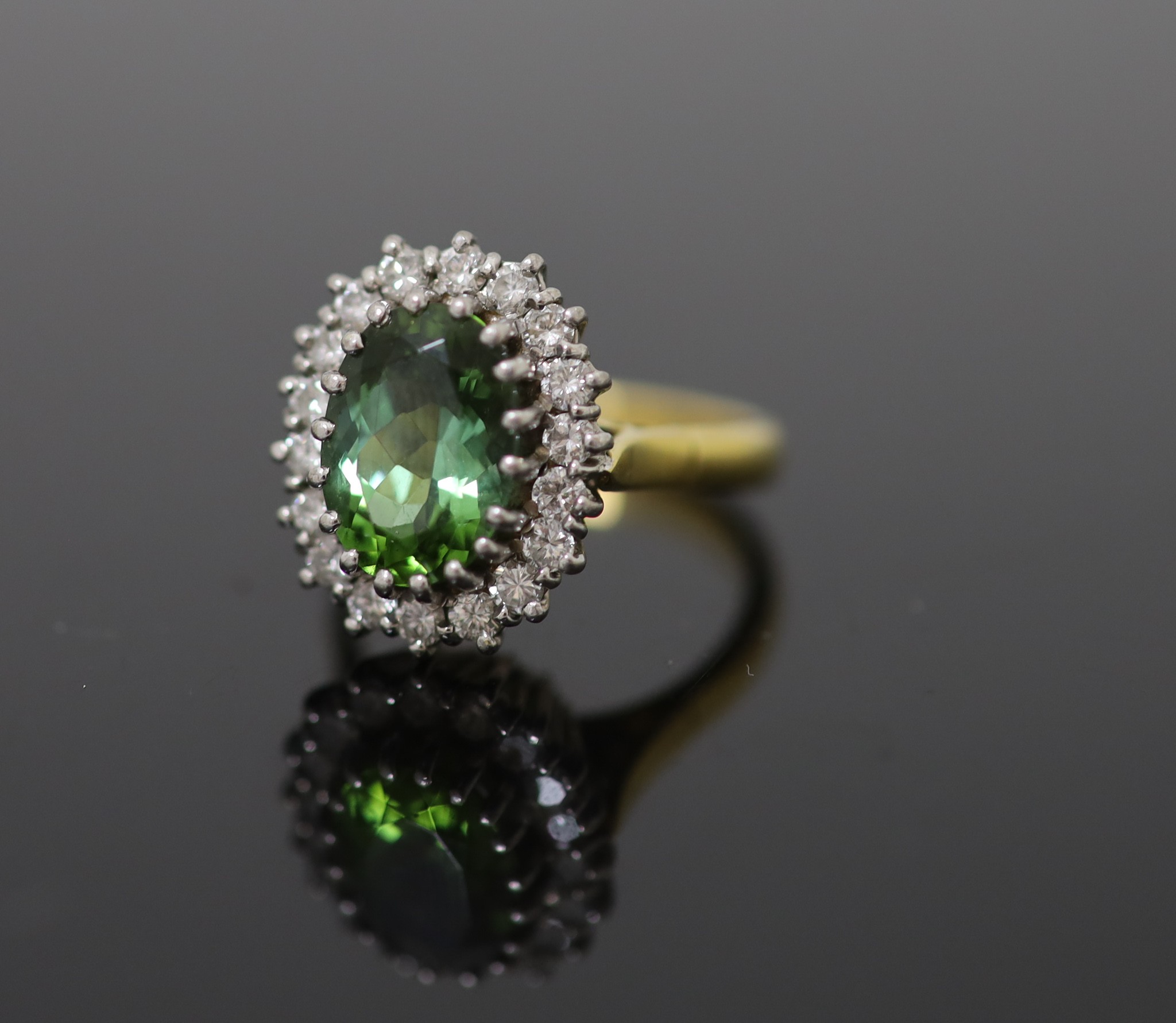 A modern 18ct gold, green tourmaline and diamond set oval cluster ring